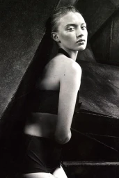 Monochrome portrait of a woman looking back over her shoulder wearing dark swimwear with make-up by April Greaves in Los Angeles.