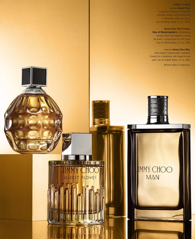 Still life shot of four golden-hued Jimmy Choo perfume bottles, each a unique design, against a reflective gold background.