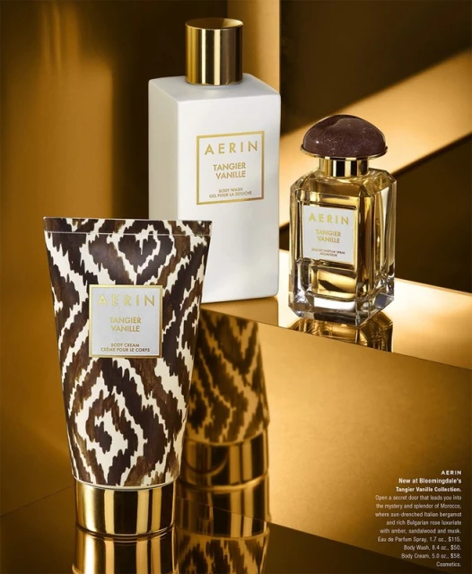 AERIN Tangier Vanille fragrance products sit on a gold reflective surface with a gold metallic background, creating a luxurious beauty shot.