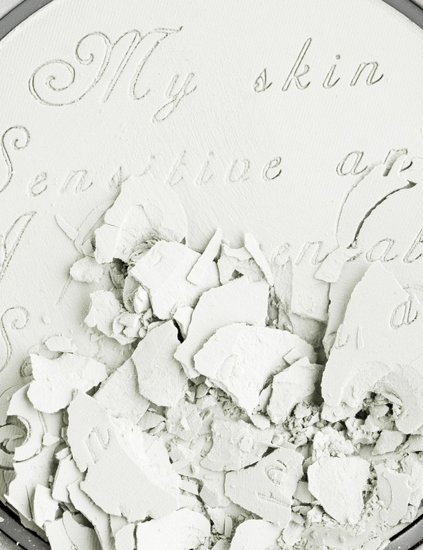Close-up of crushed white powder inside a round container, with embossed text that reads 'My skin sensitive and comfortable'.