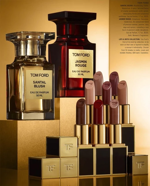 Two Tom Ford perfume bottles (Santal Blush & Jasmin Rouge) and lipstick tubes in a beauty product still life against a gold background.