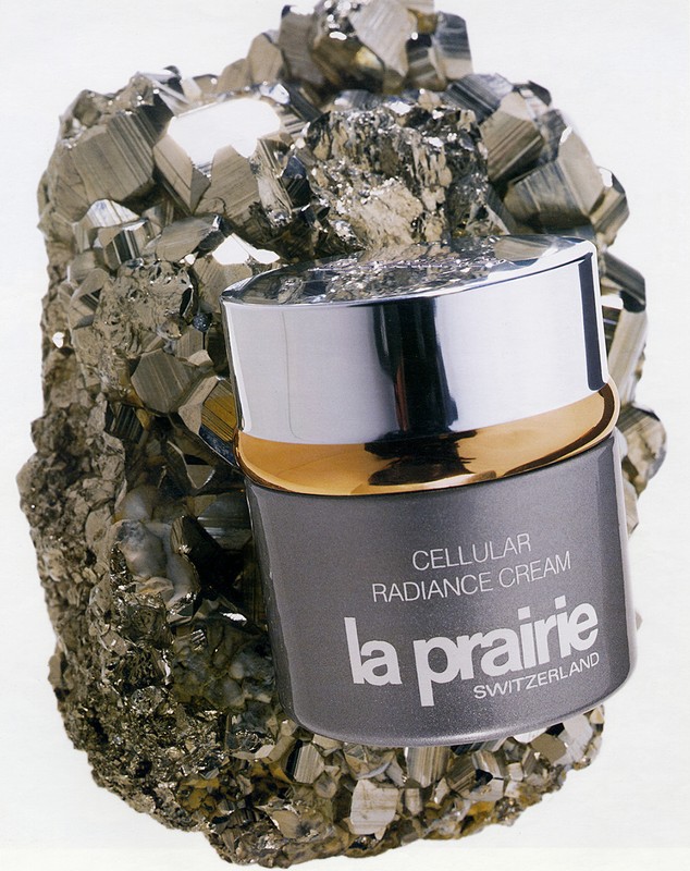 La Prairie Cellular Radiance Cream jar sits atop a textured, crystallized rock formation, set against a bright, neutral background in a product shot.