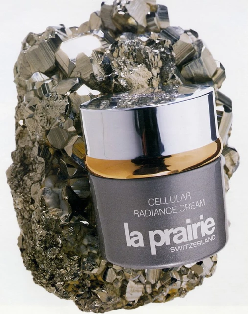 La Prairie Cellular Radiance Cream jar sits atop a textured, crystallized rock formation, set against a bright, neutral background in a product shot.