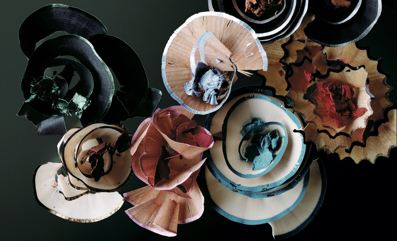 An arrangement of colorful, spiral-shaped wooden shavings creating a vibrant floral-like design on a dark background, offering a unique, textured look.