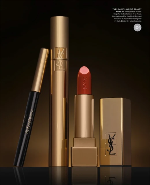Yves Saint Laurent beauty products including lipstick, mascara, and eyeliner in gold and black packaging on a dark surface.