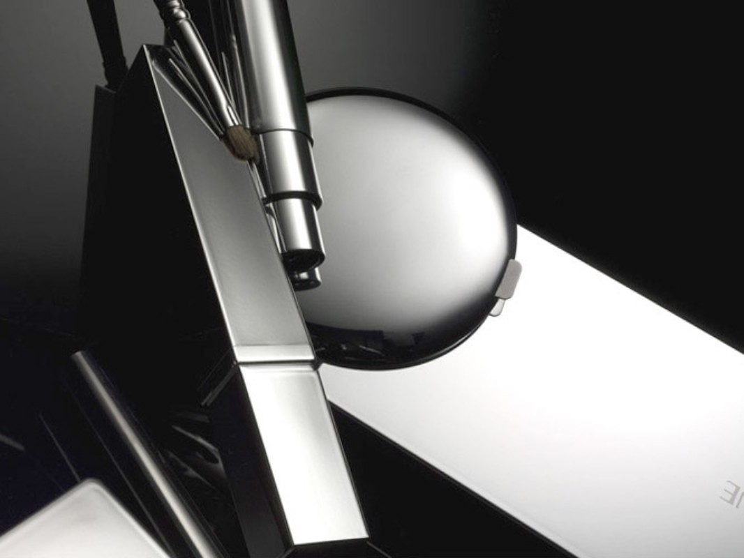 Close-up studio shot of chrome metal geometric sculpture with spherical element on dark backdrop. Geometric metal art abstract.