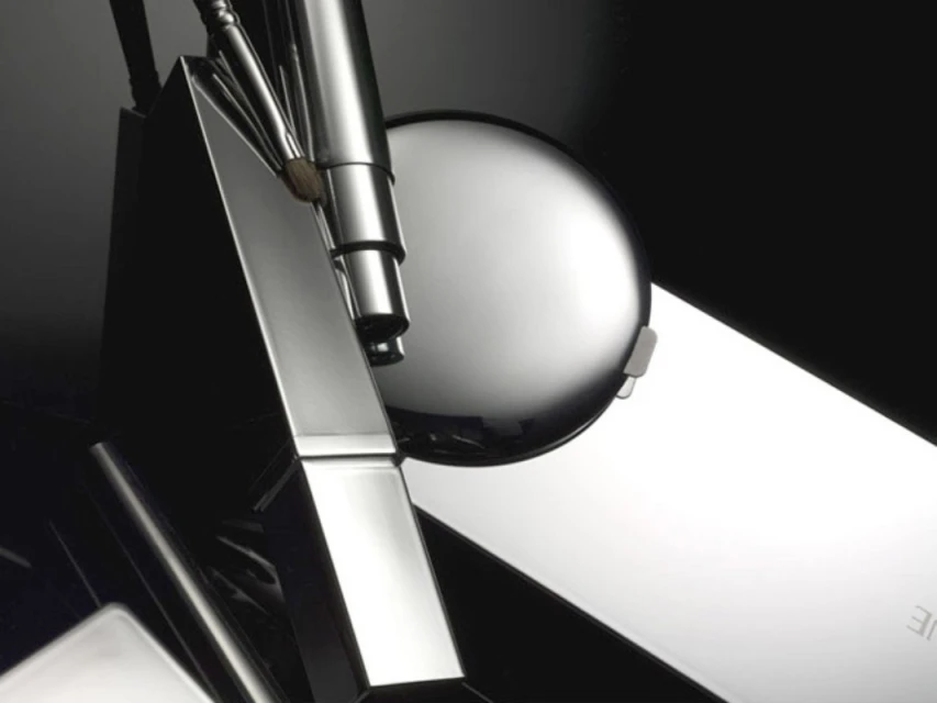 Close-up studio shot of chrome metal geometric sculpture with spherical element on dark backdrop. Geometric metal art abstract.