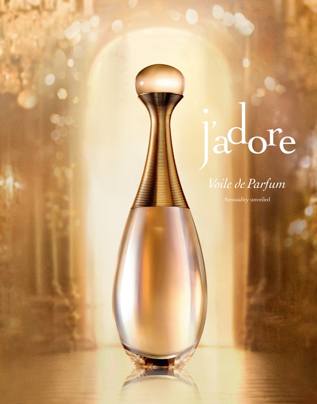 Elegant perfume bottle with a golden hue against a soft-focus background. The bottle has a distinctive shape and minimalist design aesthetic.