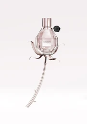 Faceted glass perfume bottle shaped like a grenade resting on a sculpted rose stem against a white background.