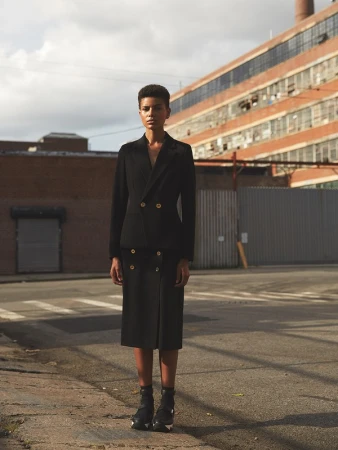 Model with short hair wearing a black double-breasted suit standing on an asphalt street in Los Angeles