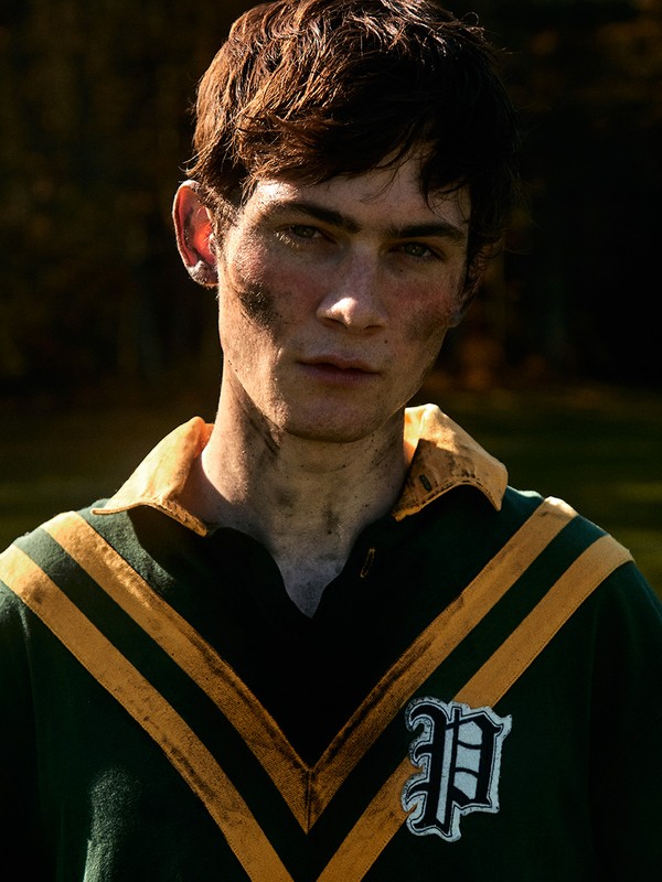 Portrait of a young man with dirty face and retro football shirt outside, capturing a blend of athleticism and vintage aesthetic.