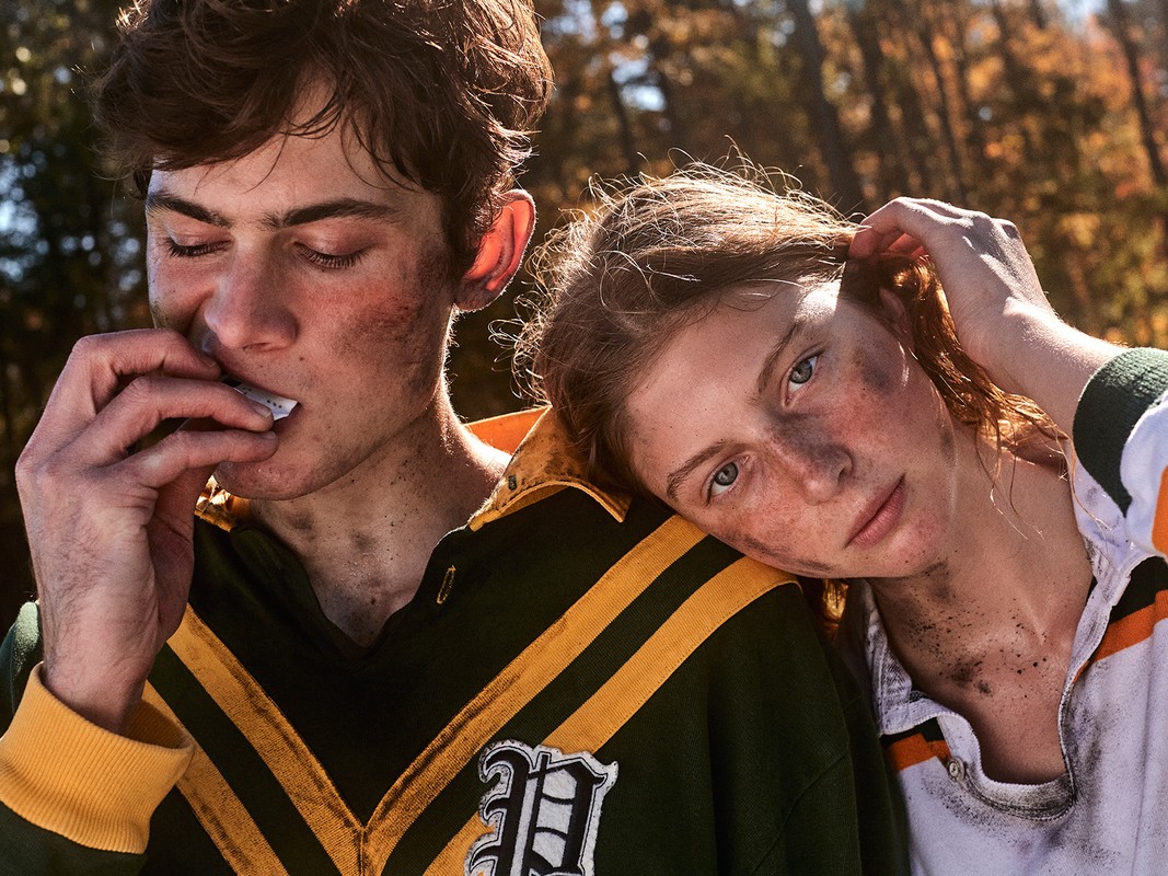 Close-up portrait of two young people with smudged faces wearing rugby shirts outdoors with autumn trees