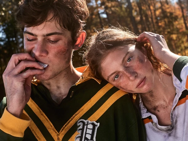 Close-up portrait of two young people with smudged faces wearing rugby shirts outdoors with autumn trees