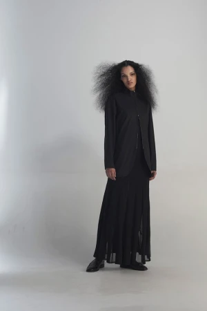 Full-length portrait of a stylish young woman with an afro in a black jacket, dress, and shoes, posing in a bright white studio.