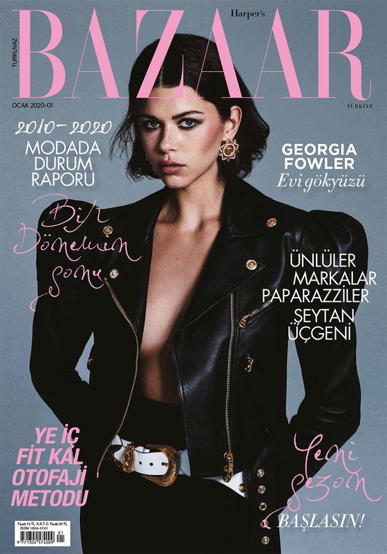 Bazaar magazine cover featuring Georgia Fowler, portrait shot, leather jacket, waist belt, and gold jewelry against a grey background.