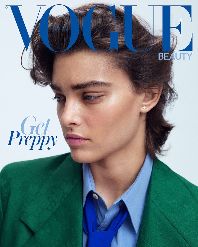Vogue magazine cover featuring a model with dark hair, wearing a green blazer, and blue shirt and tie against a bright background.