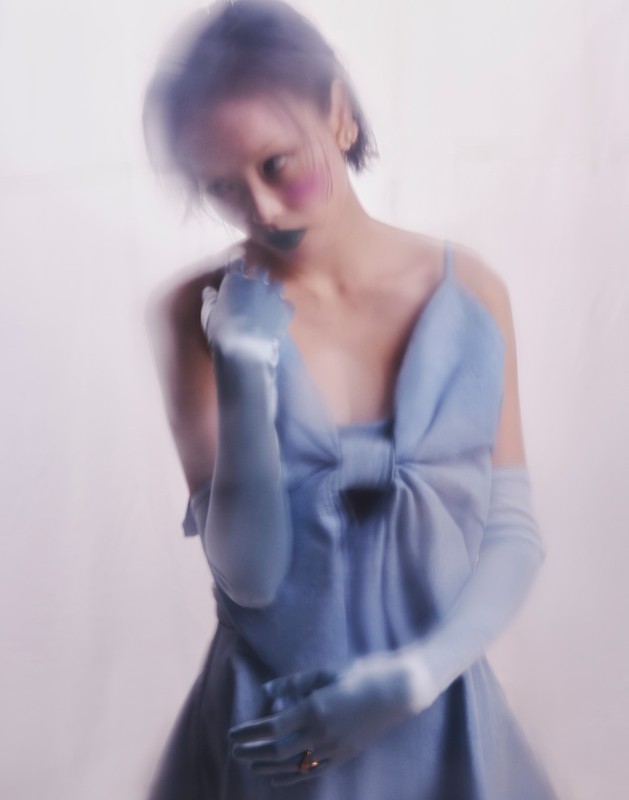 Model with motion blur wearing a light blue dress and matching opera gloves styled by Bobette Cohn