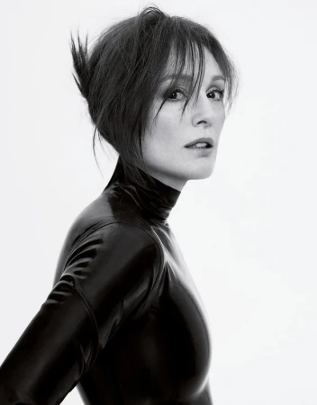 A woman with dark hair in a black latex high-neck top looking over her shoulder against a plain white background
