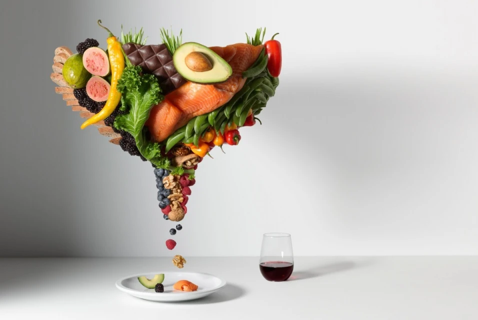 Conceptual studio shot of fruits, vegetables, salmon, chocolate, nuts, berries, and wine, representing healthy eating and a balanced diet.