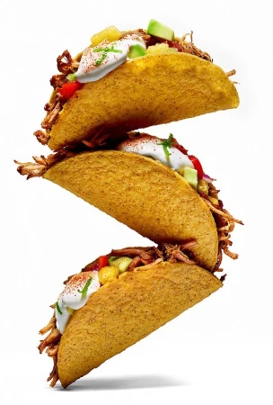 Stack of three delicious-looking tacos filled with meat, toppings, and cream, against a bright white background. Food and beverage.