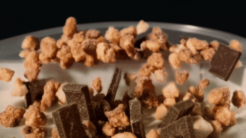 Close-up food photography of crunchy caramelized popcorn and chunks of dark chocolate on a white surface. Food and beverage.