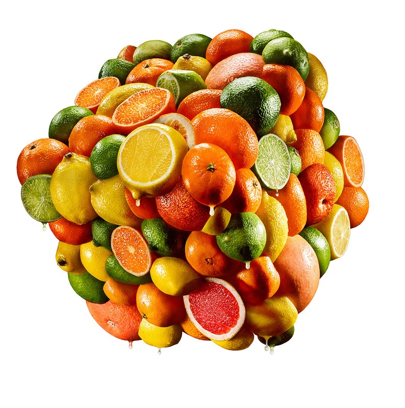 Pile of citrus fruits including oranges, lemons, limes, and grapefruits in a studio shot against a white backdrop. Fresh fruit concept.