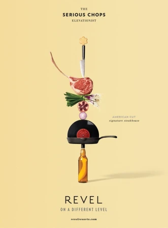 Creative food photography featuring a tomahawk steak, vegetables, frying pan, and bottle stacked on a pale yellow background.