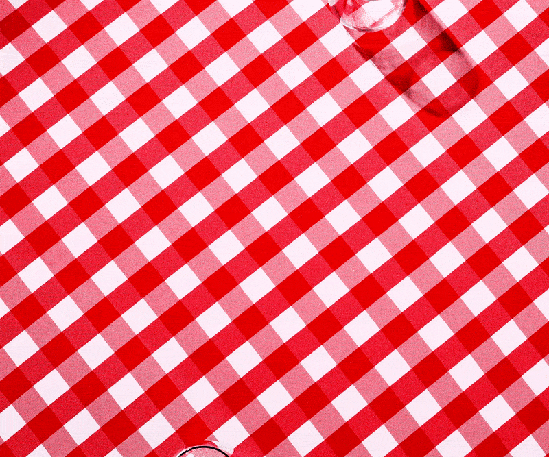 Red and white checkered tablecloth pattern dominates the frame. A blurred glass object is visible in the corner, adding a subtle accent.
