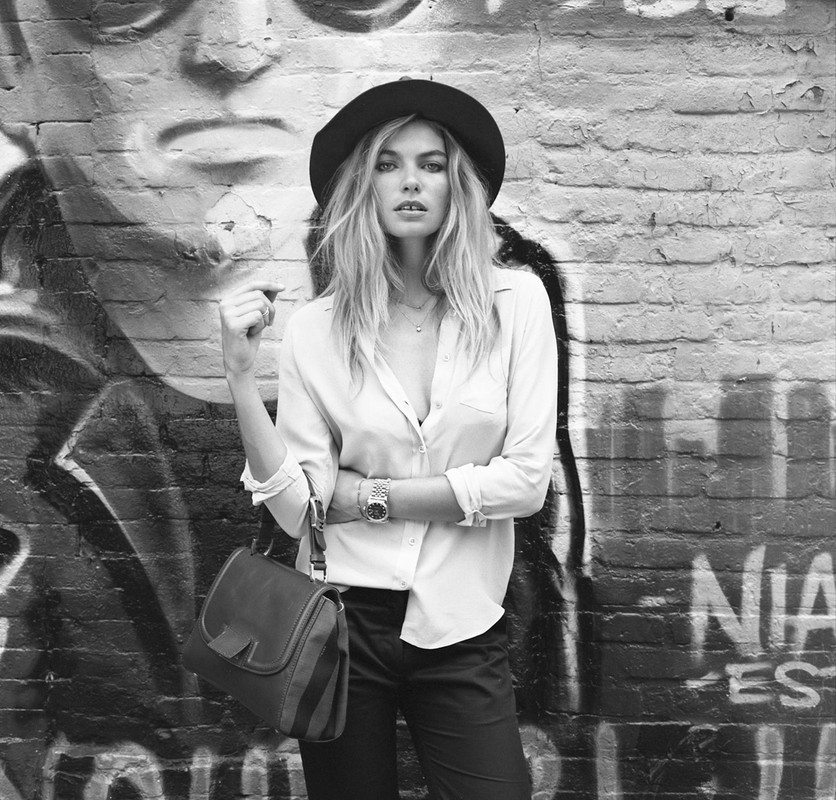 Black and white portrait of a woman wearing a wide-brimmed hat, button-down shirt, and holding a handbag in New York.