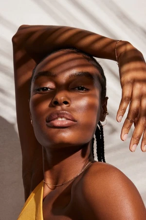 Close-up portrait of a Black woman with striped shadow cast across her face by Brooke Nipar