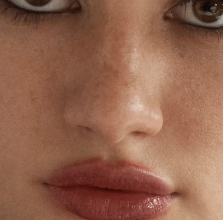 Close-up beauty portrait focusing on eyes, freckled nose, and glossy lips styled by Campbell Ritchie