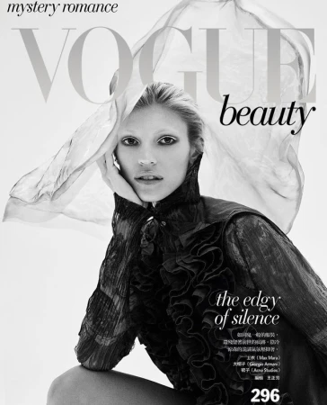 Fashion magazine cover featuring a fair-skinned model in a ruffled black top with dramatic white eye makeup, set against a light background.