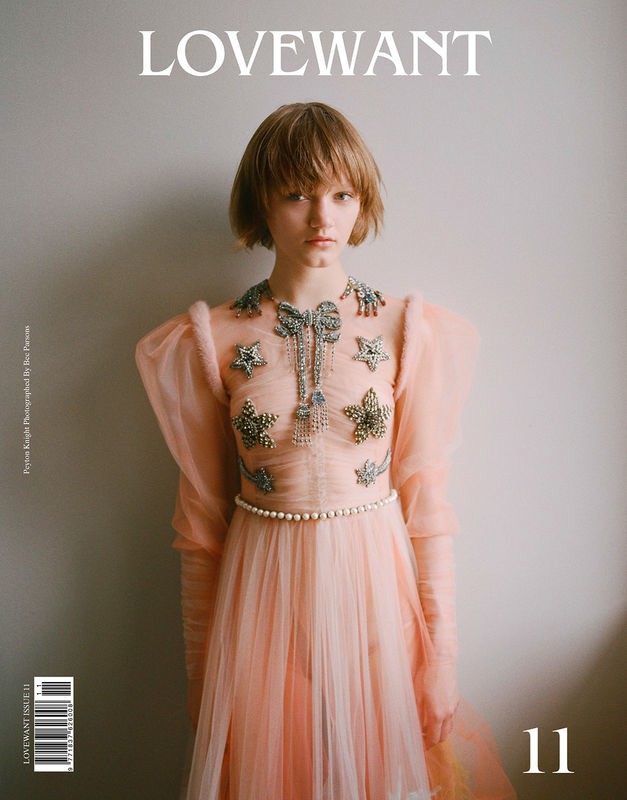 Magazine cover featuring a woman with a short bob hairstyle wearing a light pink gown with embellishments in a studio setting.
