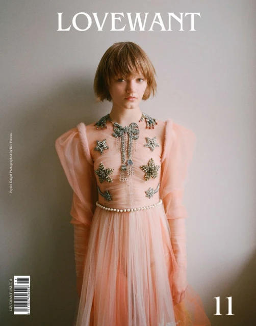 Magazine cover featuring a woman with a short bob hairstyle wearing a light pink gown with embellishments in a studio setting.
