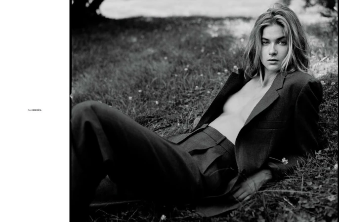 Black and white portrait of a woman lying on grass wearing a tailored suit jacket