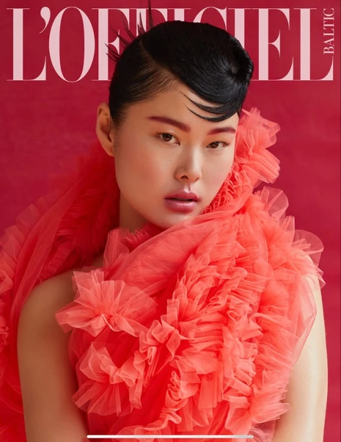 Magazine cover featuring a portrait of a woman with dark hair and red tulle ruffles against a red background with the magazine title visible.