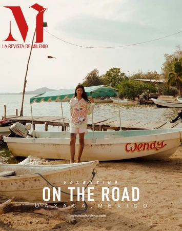 Magazine cover featuring a female model in casual clothing standing in front of a boat, with a beach and body of water as backdrop.