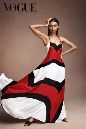 Fashion editorial shot of an Indian woman posing in a red, black, and white flowing dress with the Vogue India logo in the upper left corner.