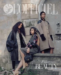 Three models posing against an old stone architectural exterior with textured masonry and carved columns