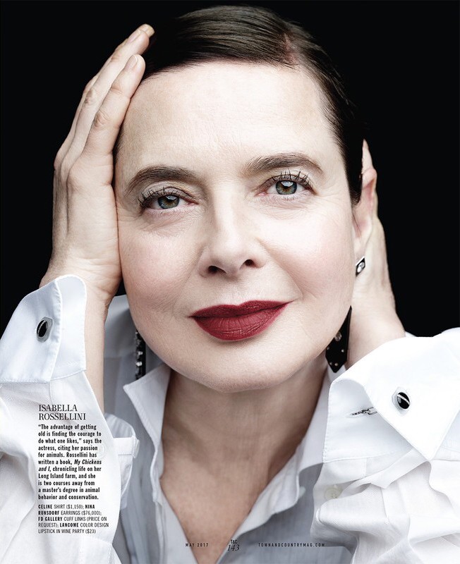 Portrait of Isabella Rossellini with hands near her face wearing a white collared shirt against a dark background in a magazine spread.