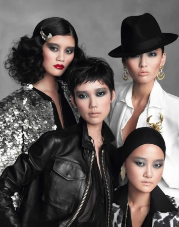 Four Asian women in diverse fashion styles pose in a studio portrait with black and white outfits and dramatic makeup against a grey background.