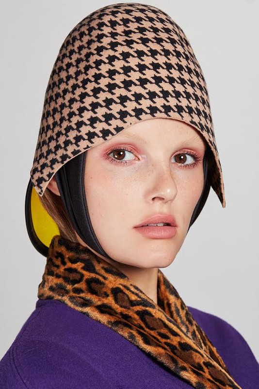 Woman in patterned headwear and leopard print collar. Close-up portrait, studio shot with a neutral background, and soft, diffused lighting.