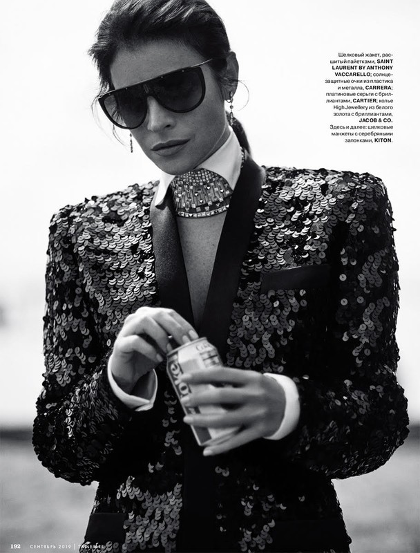 Fashion shot of a woman in a sequined blazer and sunglasses, holding a can. Black and white image with a shallow depth of field.