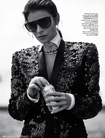 Fashion shot of a woman in a sequined blazer and sunglasses, holding a can. Black and white image with a shallow depth of field.