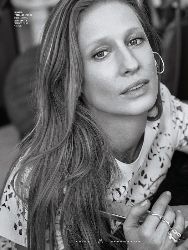 Close-up black and white portrait of a woman with long hair wearing hoop earrings and multiple rings, makeup by Chris Colbeck.