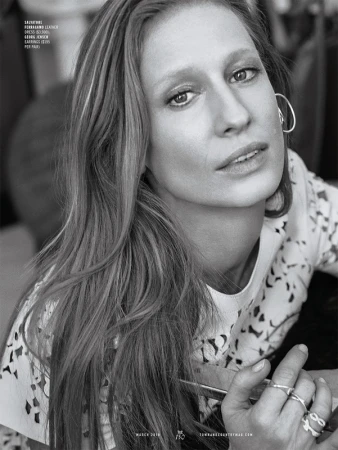 Close-up black and white portrait of a woman with long hair wearing hoop earrings and multiple rings, makeup by Chris Colbeck.
