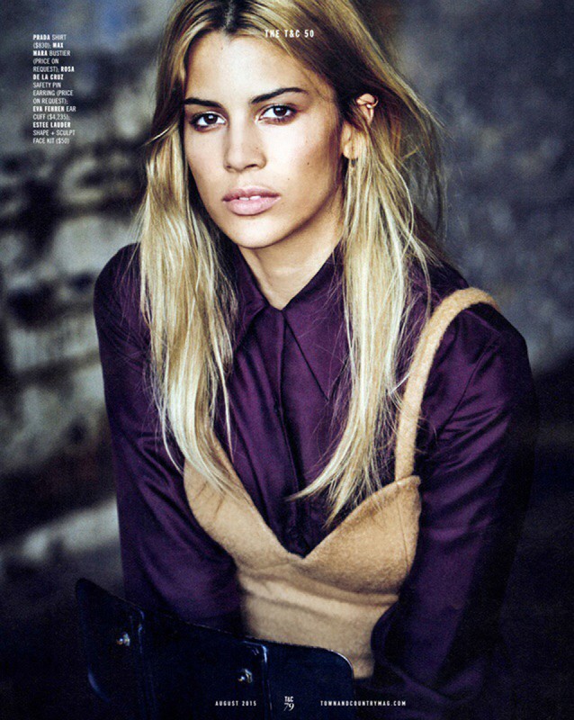 Close-up fashion portrait of a blonde adult female wearing a purple collared shirt and tan tank top in a studio setting.