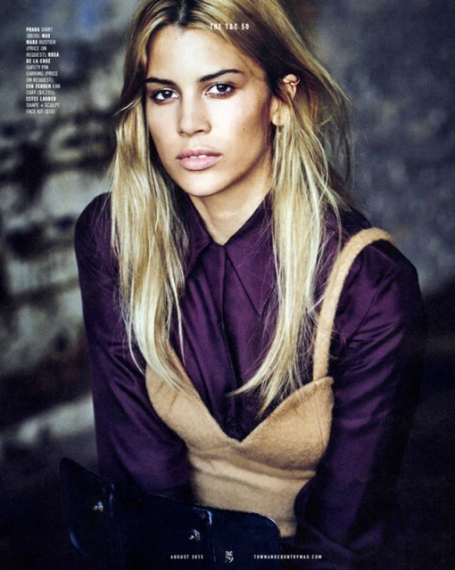 Close-up fashion portrait of a blonde adult female wearing a purple collared shirt and tan tank top in a studio setting.