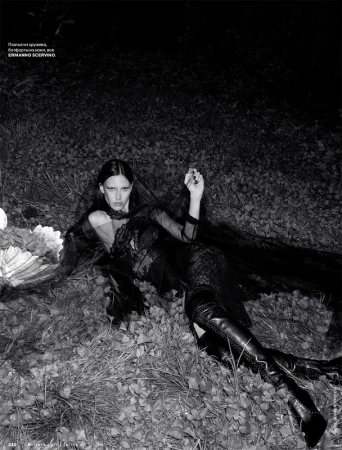 Model in black lace dress and leather boots lying on grass outdoors at night with make-up by Chris Colbeck