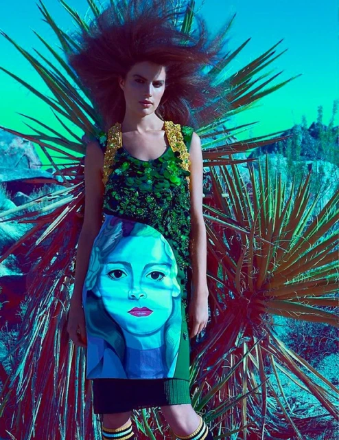 A stylish fashion shot features a model in an embellished green dress with an illustrated face, standing in a desert landscape with sparse plants.